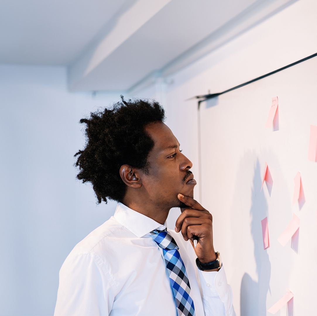 A professional thinks through a decision in front of a whiteboard